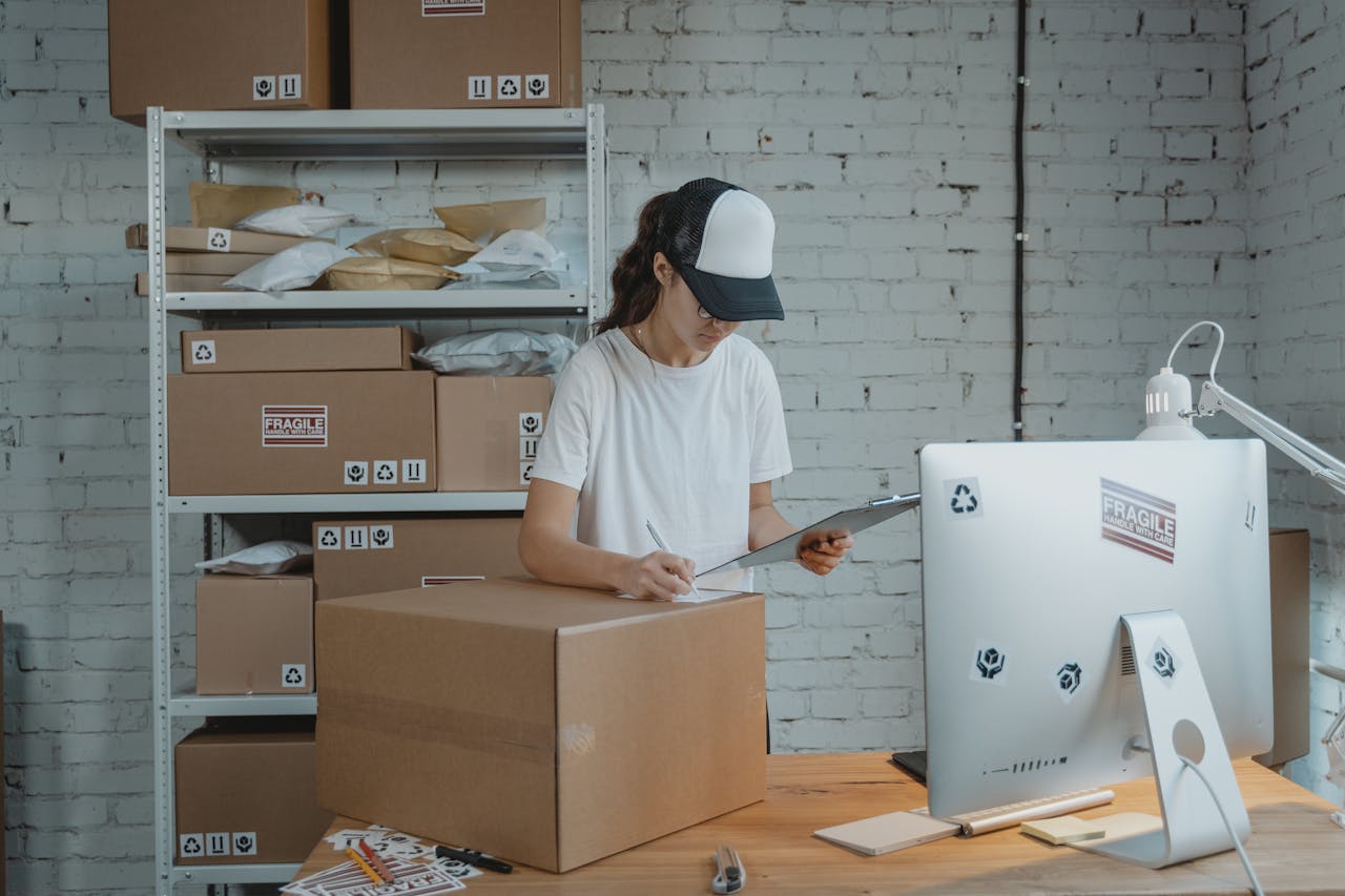Woman writing down on a Carton Box while looking at a Clipboard